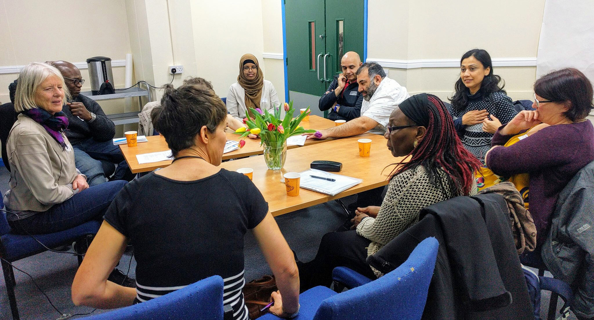 Ten people round a table talking in a workshop