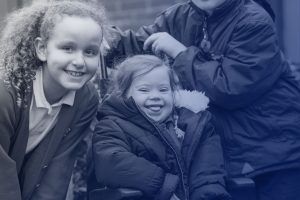 Two schoolgirls smiling, one with Down's Syndrome