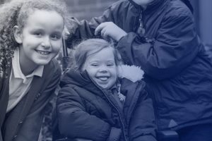 Two schoolgirls smiling, one with Down's Syndrome