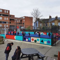 The school playground containing the new astroturf pitch, with girls and boys playing football on it