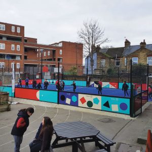 The school playground containing the new astroturf pitch, with girls and boys playing football on it