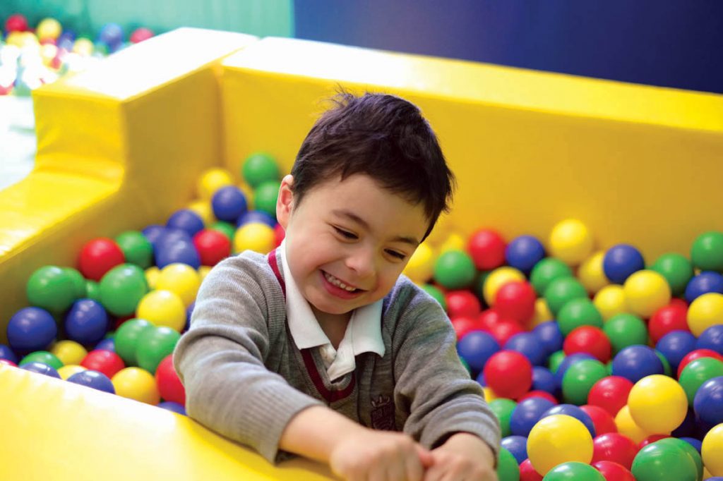 small boy in ballpit, wearing school uniform