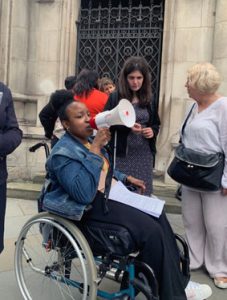 Yewande from ALLFIE speaking through a loudspeaker. Yewande is a wheelchair user.