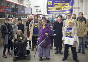 ALLFIE and supporters in Whitehall with banner saying 'We Know Inclusion Works'