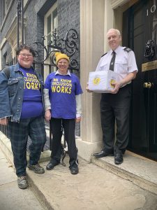 A Government official accepts the petition from Martine Harding and Simone Aspis on the steps of 10 Downing Street