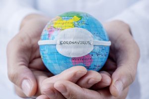 Doctor holding in hands a world globe with the word coronavirus