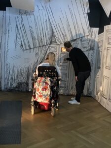 Image of Grace and companion at an exhibition, shot from behind