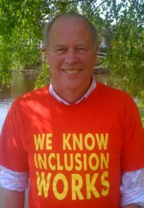 Photograph of Joe Whittaker, smiling to camera and wearing a red shirt with the slogan: 'We Know Inclusion Works'