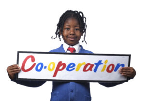 Monega Primary School 3, pupil holding a sign with the text 'Co-operation'. Copyright: Monega Primary School