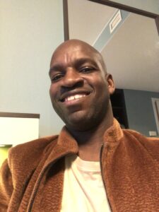 Image: Edmore Masendeke, Author. Close-up shot of Edmore, a Black man, smiling at the camera.